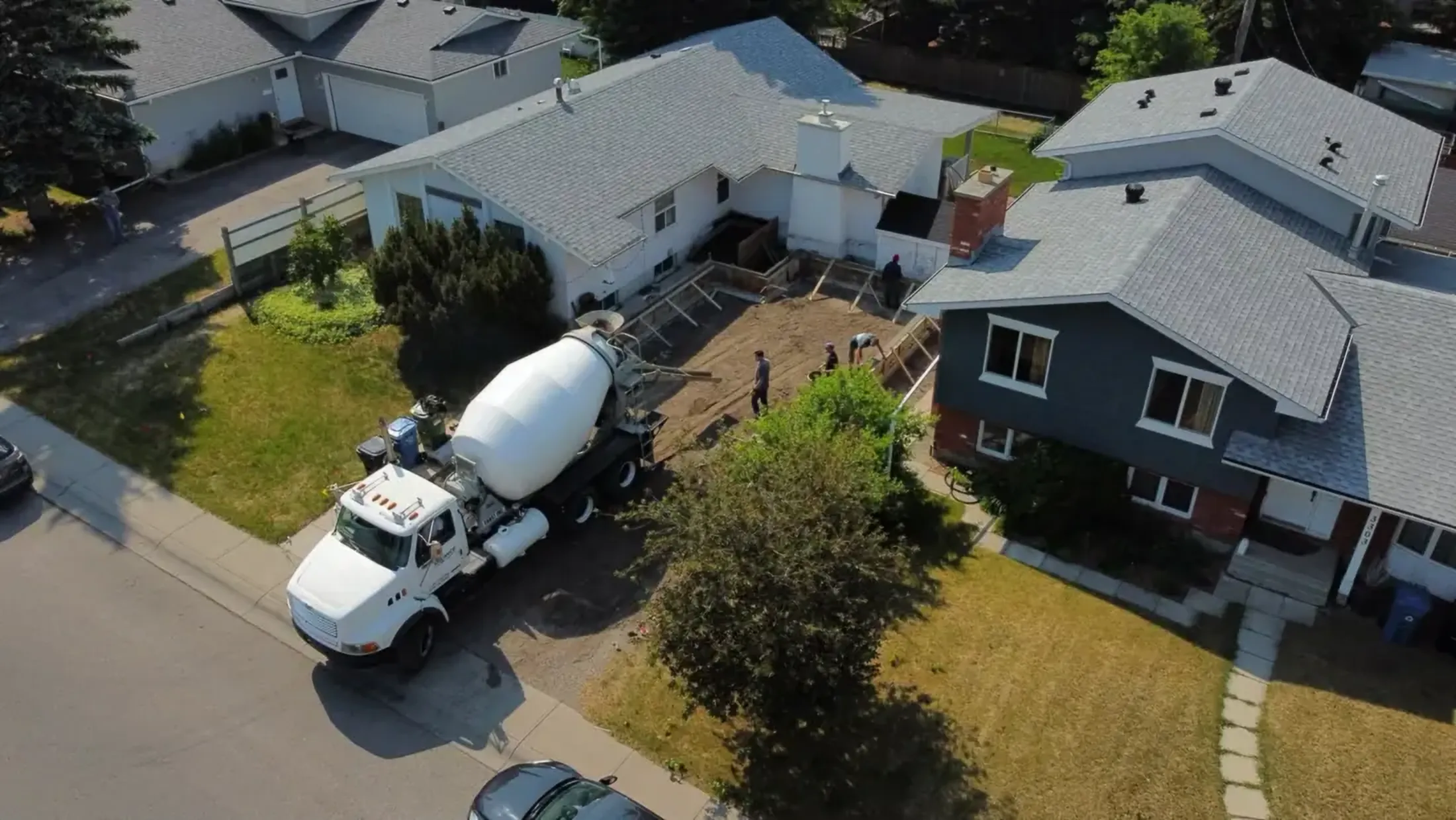 An aerial view of a concrete truck pouring at a house