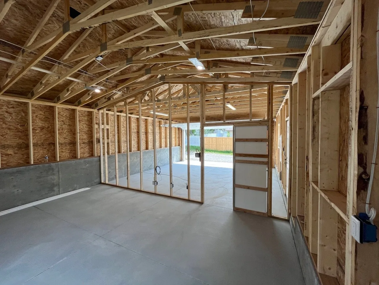 A garage interior with a framed partition wall going in and roughed-in electrical boxes
