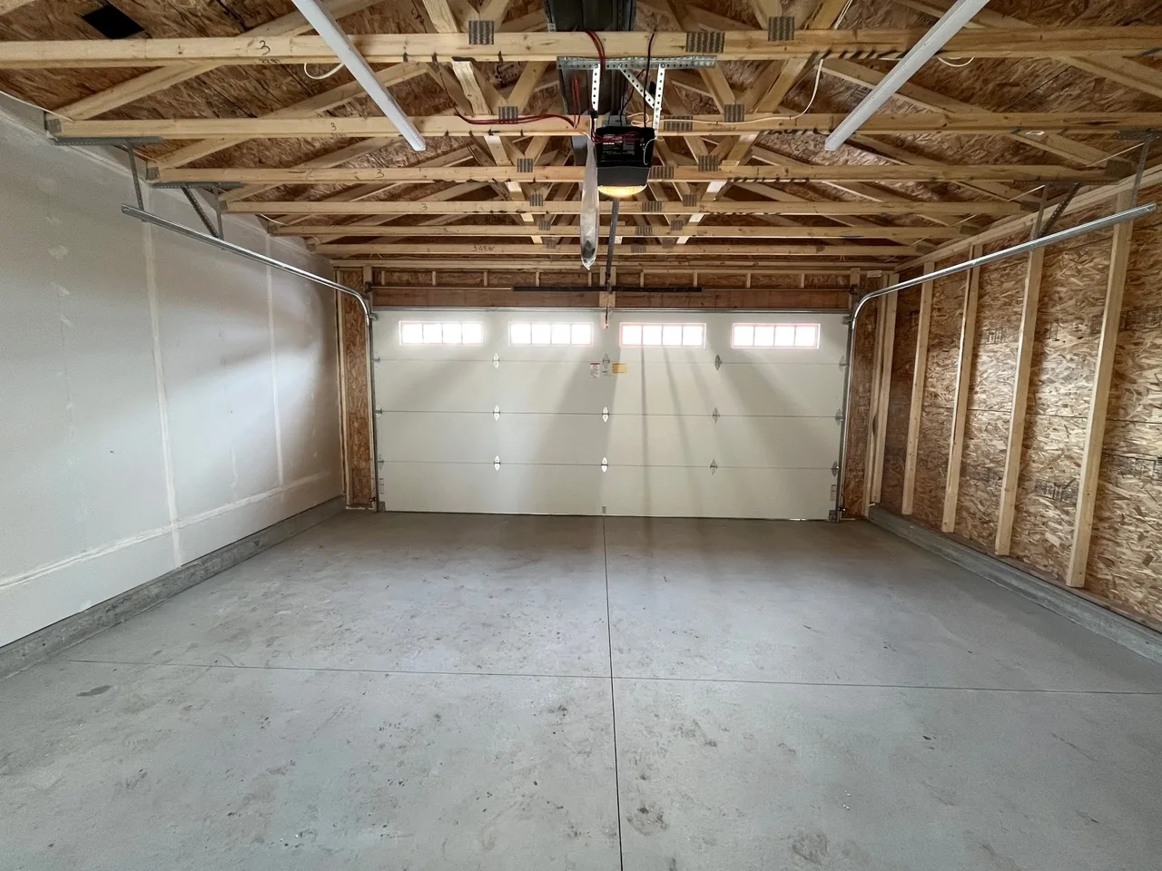 A garage interior with exposed trusses and a door with window lites