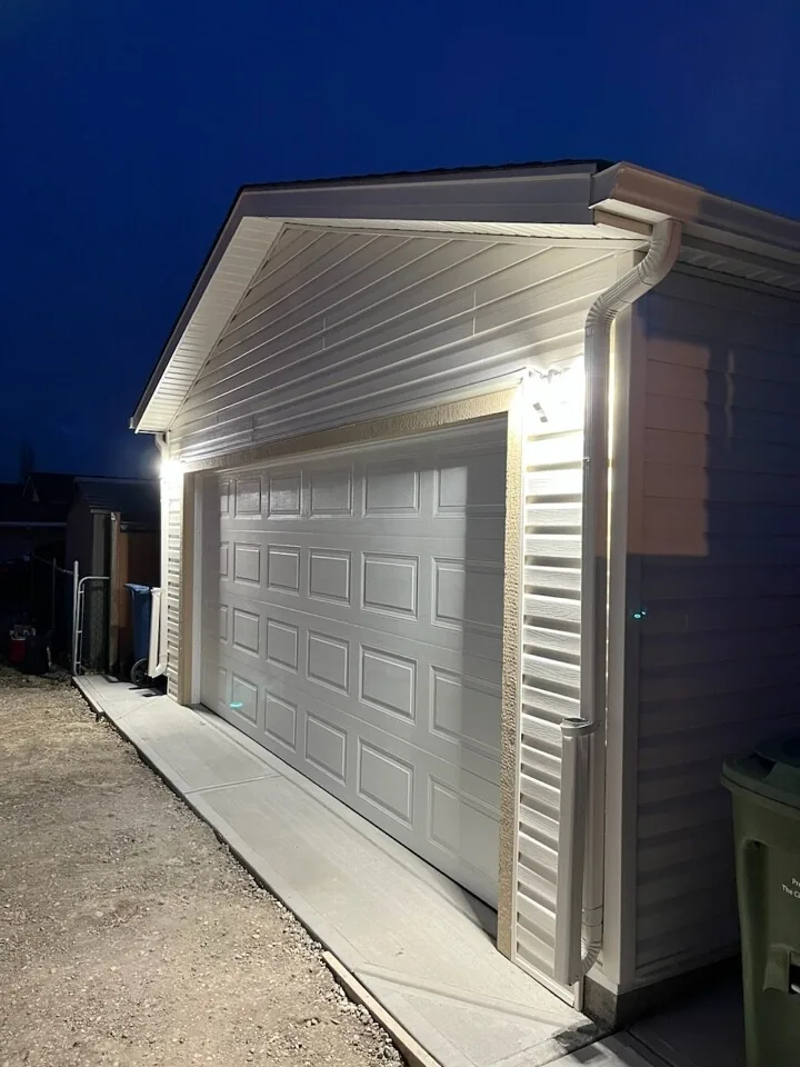 A new garage lit at night with a fresh concrete apron