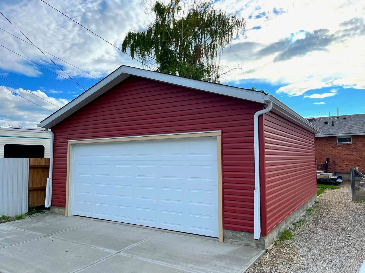 A new red-sided garage with a fresh concrete pad