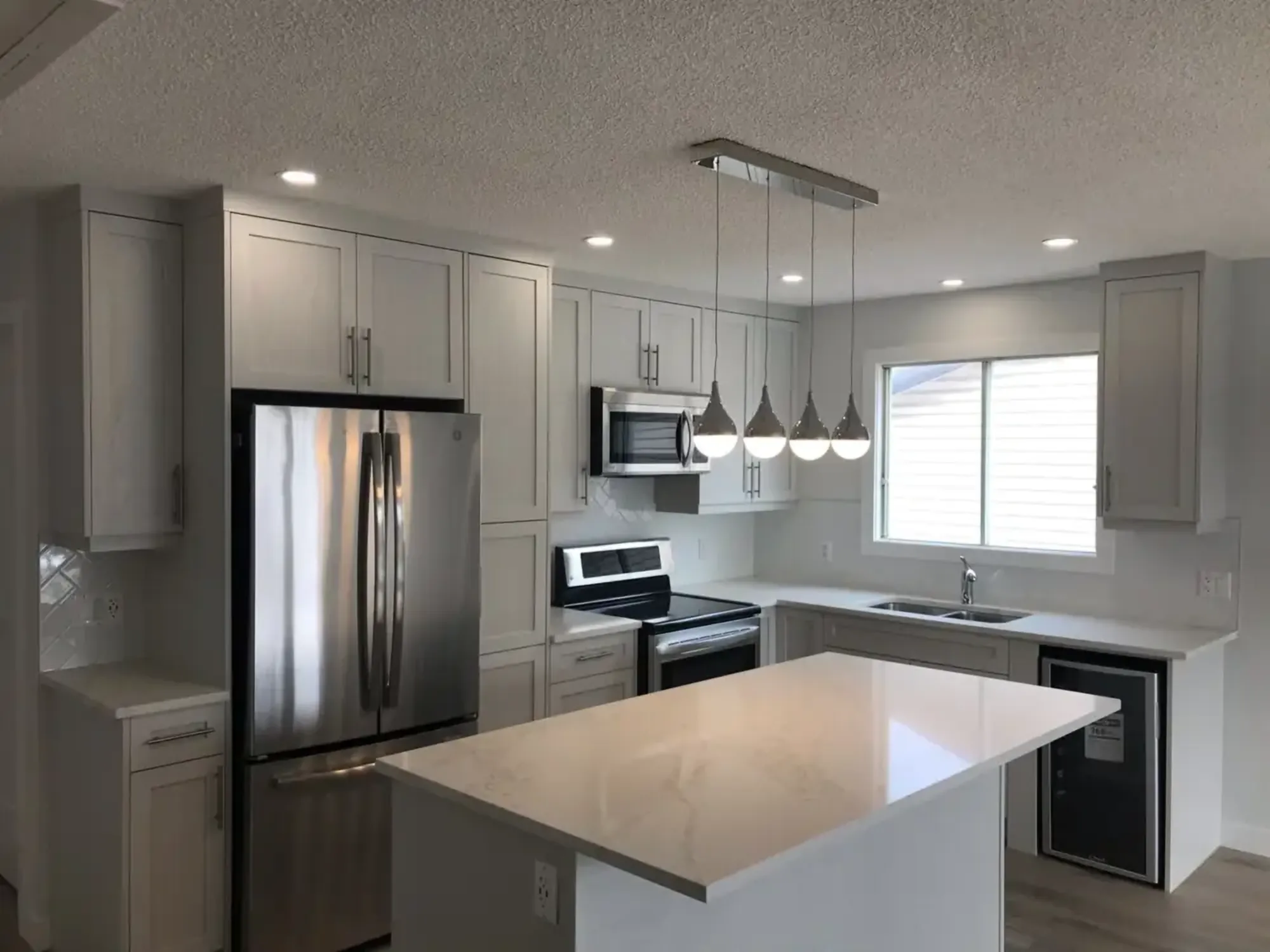 A bright renovated kitchen with shaker cabinets, an island and pendant lights